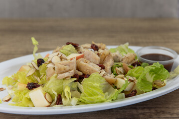 Hearty salad loaded high on the plate topped with raisins and stacked