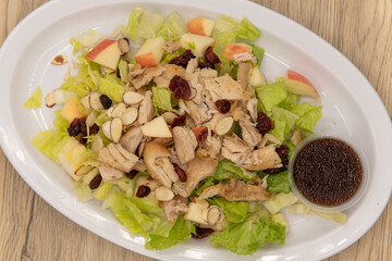 Overhead view of hearty salad loaded high on the plate topped with raisins and stacked