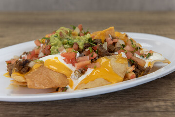 Hearty plate of nachos smothered with melted cheese, pico de gallo, and sour cream to serve as a meal