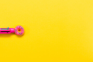 Pink pen in the form of a donut isolated on a yellow background. Multi-colored pen. Back to school