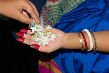 Top angle view of hands with Flowers. Hindu woman taking flowers for puja in the temple.