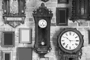 Monochrome vintage clock and picture frame hanging on an brick wall