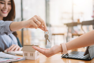 Client taking keys from female real estate agent during meeting after signing rental lease contract or sale purchase agreement. Independent woman purchasing new home, close up view.