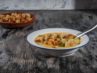 Vegetable puree soup with croutons and fresh herbs in a white plate and croutons