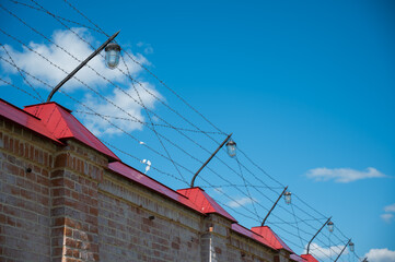 Barbed wire on the fence of the prison against the blue sky