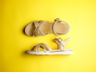 Close up of beige leather summer comfortable women's sandals on brigth yellow paper background. Top view, side view, flat lay, horizontal, copy space