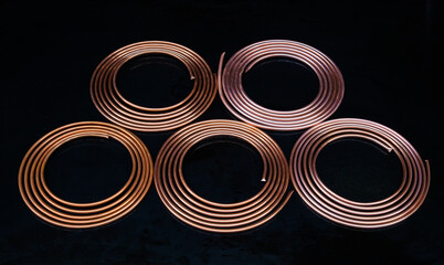 Twisted new copper tubes on a black background.