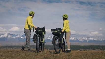 The man and woman travel on mixed terrain cycle touring with bikepacking. The two people journey...