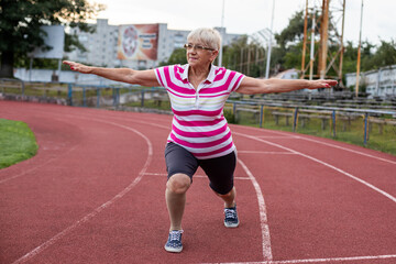 Fototapeta premium older woman doing gymnastics and running in the stadium, person running