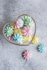 Fototapeta na wymiar Small colorful meringues in the heart shaped bowl