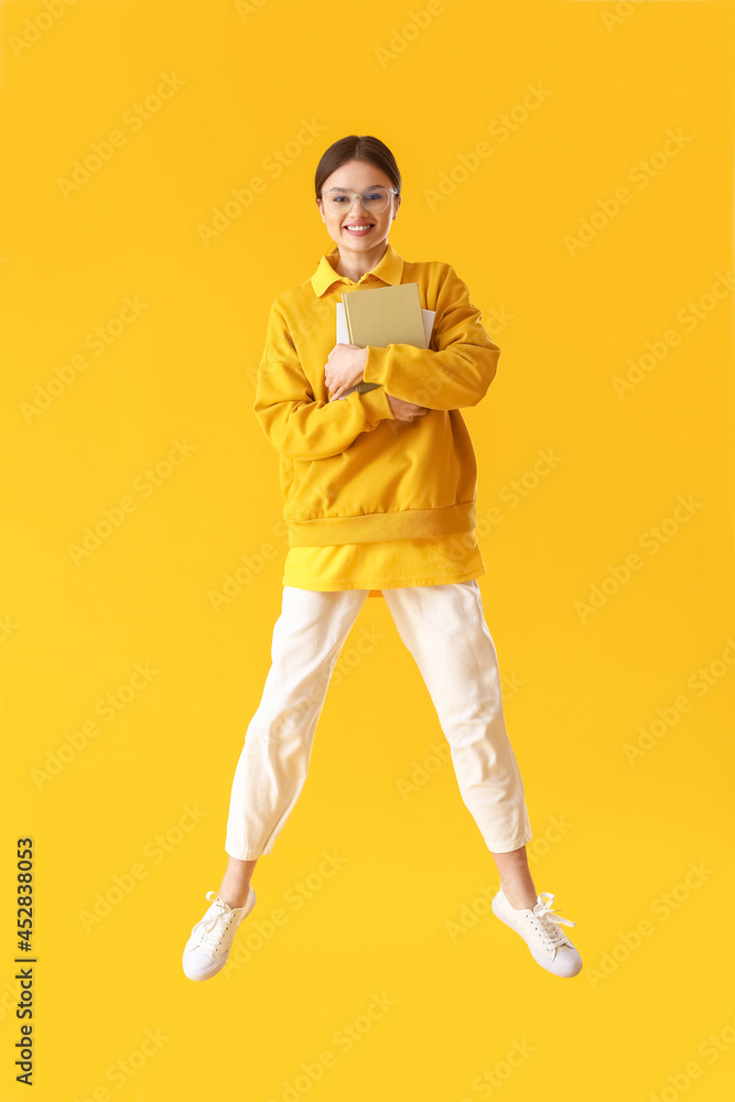 Canvas Prints Jumping young woman with books on color background