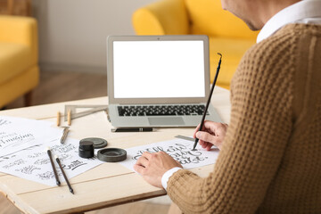 Young male calligrapher working in office