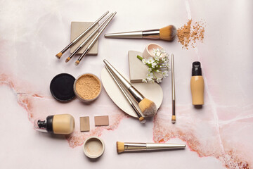 Set of makeup brushes with decorative cosmetics on light background
