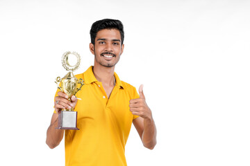 young indian man holding a trophy and doing winner gesture