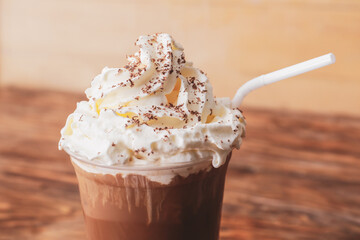 Glass of tasty iced coffee with whipped cream on table, closeup