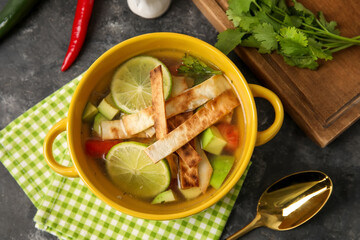 Bowl of tasty Sopa de Lima soup on dark background