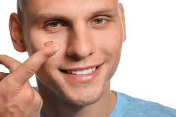 Obraz premium Young man putting in contact lenses on white background