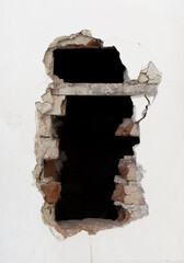 Picture white broken wall with black hole and bricks.