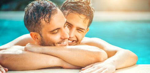 Gay couple relaxing in swimming pool. LGBT. Two young men enjoying nature outdoors, kissing and hugging. Young men romantic family in love. Happiness concept
