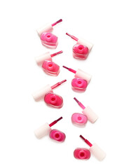 Opened bottles of nail polishes and brushes on white background