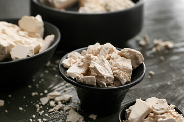Bowls with fresh yeast on dark wooden background