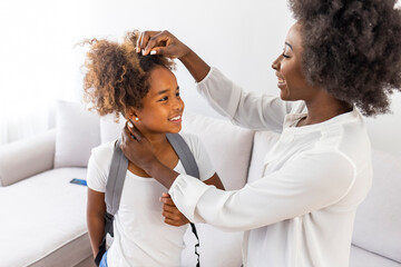 Fototapeta premium Mom gets daughter ready for school in the morning. Mother preparing her daughter for first day in school. Mother leads little child school girl in first grade. Mother preparing her child for school