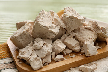 Board with fresh yeast on wooden background
