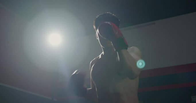 Boxer man fighting with red boxing gloves punching air exercise training in fitness gym, fit sport healthy lifestyle workout concept