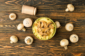 Bowl with tasty mashed potatoes and mushrooms on wooden background