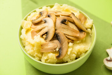 Bowl with tasty mashed potatoes and mushrooms on color background, closeup