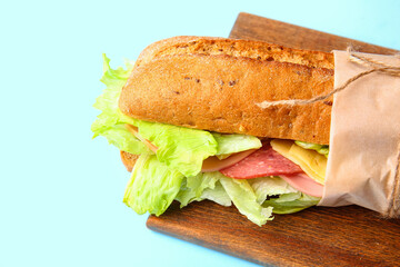 Board with tasty ciabatta sandwich on color background, closeup