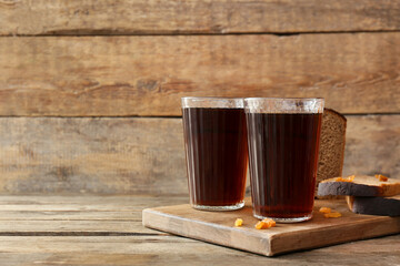 Glasses of fresh kvass, raisins and bread on wooden background