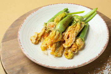 Plate with fried zucchini flowers on color background, closeup