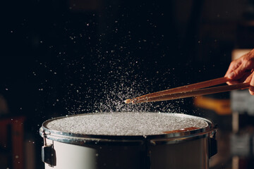 Close up drum sticks drumming hit beat rhythm on drum surface with splash water drops