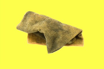 Old dirty torn rag isolated on yellow background. Cleaning rag