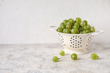 Colander with fresh ripe gooseberry on table