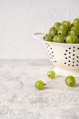 Colander with fresh ripe gooseberry on table