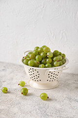 Colander with fresh ripe gooseberry on table