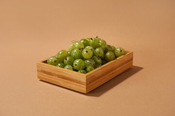 Box with fresh ripe gooseberry on color background