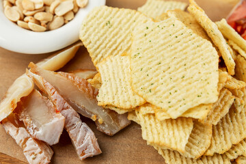 Appetizing dry snacks for beer. Chips, fish and nuts on a wooden board. Close-up.