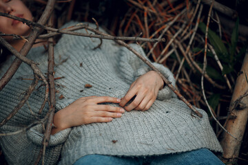 Teenager young woman lying outdoor in the park under dry tree branches. Sex maniac crime rape violence concept