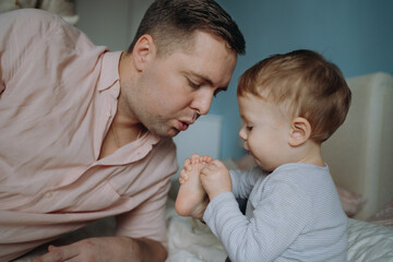 father and son. Man blowing on son's toe to cool down and ease pain. Image with selective focus
