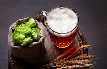 Lager beer mug, hops and wheat on old barrel