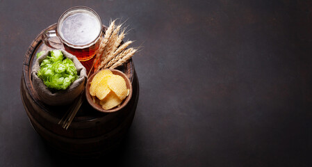 Lager beer mug, hops and wheat on old wooden barrel