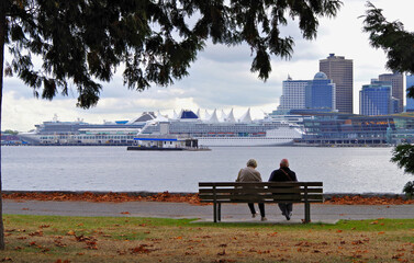 Couple romance sitting on park bench in Stanley Park, Vancouver Canada with picturesque city...