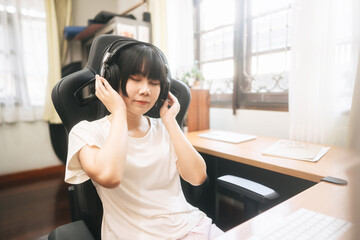Young adult asian woman stay at home  wear headphone listening music online.