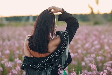 Young brunette woman on blooming Sally flower field. Lilac flowers and girl