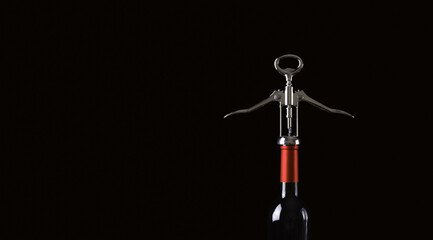 Metal bottle opener on a glass wine bottle on a black background. Free space for text.