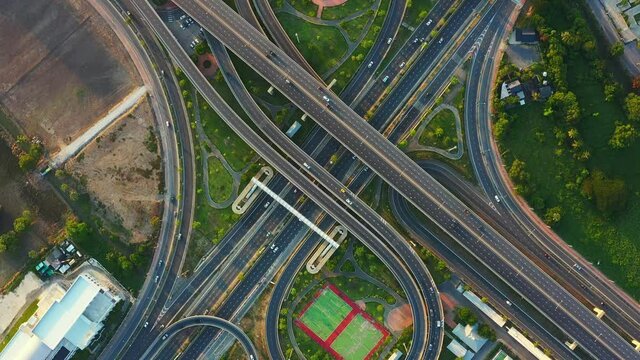 Time lapse of aerial view of highway junctions with roundabout. Bridge roads shape circle in structure of architecture and transportation concept. Top view. Urban city, Bangkok at sunset, Thailand.