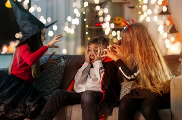 halloween, holiday and childhood concept - smiling boy and girls in costumes playing and scaring...